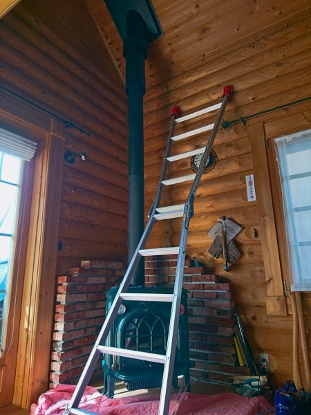 梯子を立てて薪ストーブの室内煙突パイプを外す
